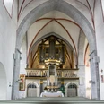 Innenansicht einer gotischen Kirche mit beeindruckender Orgel auf der Empore und hohen Gewölben.