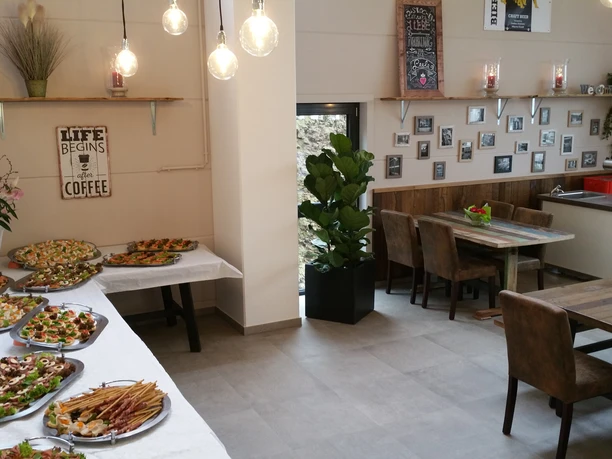 Cateringbereich Gemütliches Café mit rustikalen Holztischen, dekoriert mit leckerem Fingerfood und charmanten Details.