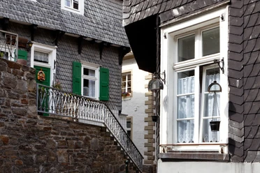 Bücher- und Altstadt Velbert-Langenberg Fachwerkhäuser mit Schieferschindeln, grünen Fensterläden und Blumenschmuck in malerischer Gasse.