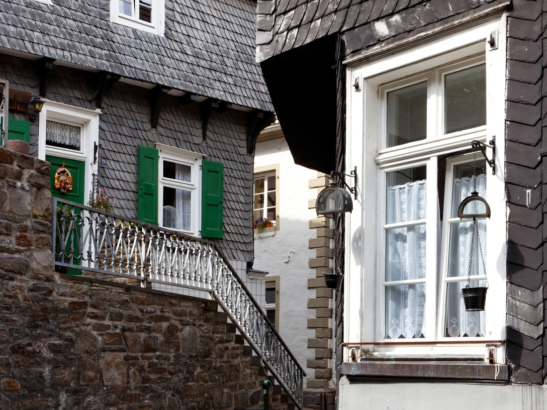 Bücher- und Altstadt Velbert-Langenberg Fachwerkhäuser mit Schieferschindeln, grünen Fensterläden und Blumenschmuck in malerischer Gasse.
