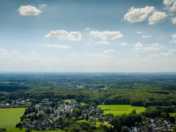 Domblick bei Odenthal-Voiswinkel Weitläufiges Panorama über eine grüne Landschaft mit Wäldern, Feldern und verstreuten Häusern unter blauem Himmel.