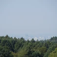 Domblick Voislöhe Blick auf Köln im Dunst, mit dem Kölner Dom in der Ferne, umgeben von bewaldeter Landschaft.