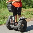 Mit dem Segway unterwegs im Bergischen Land Mann fährt auf einem Segway über einen gepflasterten Weg durch eine grüne, bewaldete Umgebung.