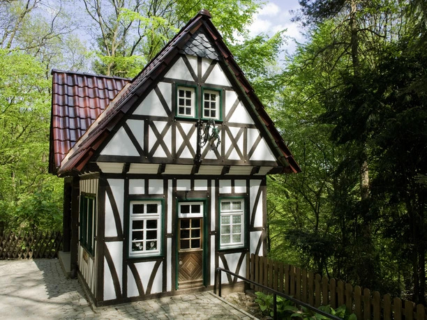 Märchenwald Altenberg Fachwerkhaus mit rotem Ziegeldach, umgeben von dichtem Wald, bei sonnigem Wetter aufgenommen.