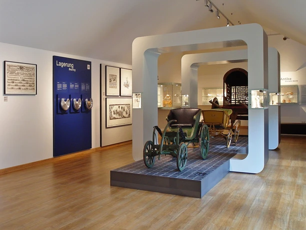 Ausstellungsraum im Museum Achse, Rad und Wagen Historische Ausstellung mit antiken Fahrzeugen in einem modern gestalteten Museumsraum.