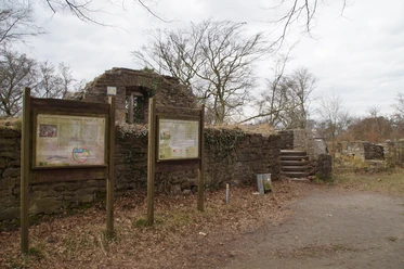Reste der Isenburg in Essen Ruinen einer alten Steinburg mit Informationstafeln, kahlen Bäumen und bewölktem Himmel.