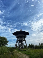 Foto Eggeturm.jpeg Ein hölzerner Aussichtsturm erhebt sich unter einem blauen Himmel mit verstreuten Wolkenformationen.