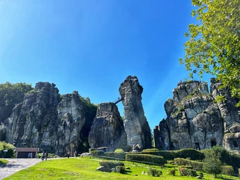 Foto Externsteine.jpeg Die Externsteine sind beeindruckende Sandstein-Felsformationen unter klarem, blauem Himmel umgeben von Bäumen.