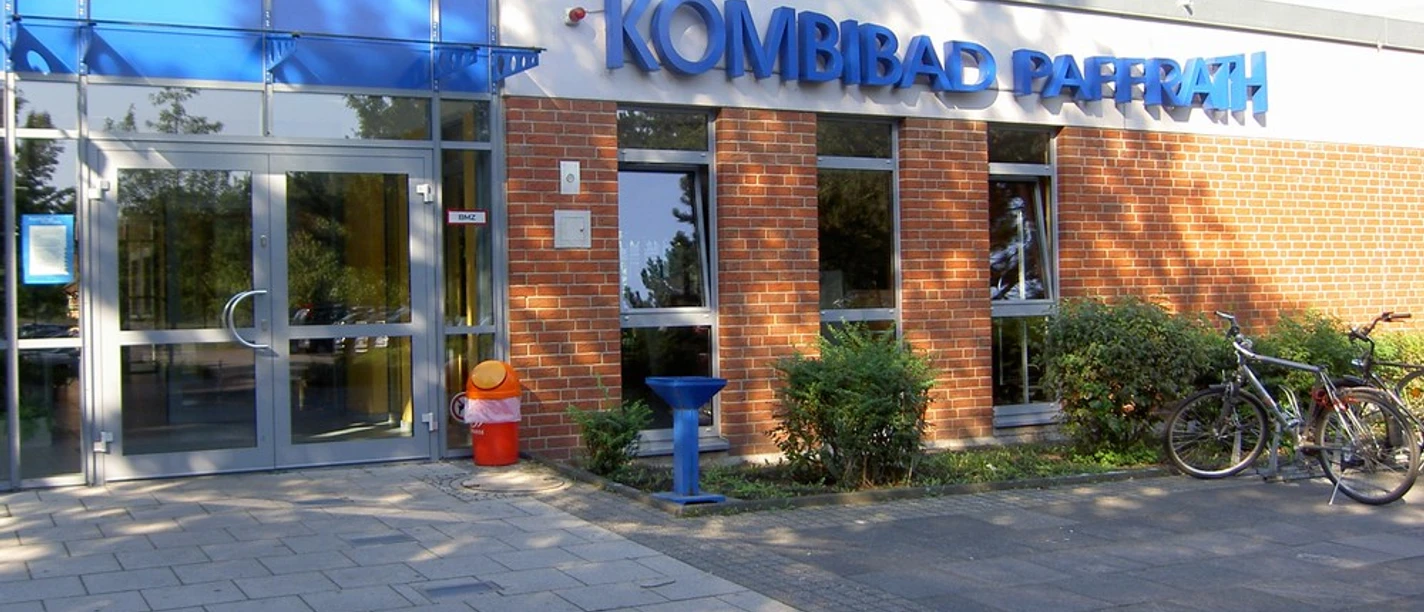 Kombibad Paffrath Das Bild zeigt den Eingang des Kombibads Paffrath mit blauen Fenstern und Ziegelwänden.