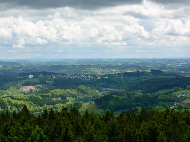 Blick auf die Aggertalsperre Blick über eine grüne, bewaldete Landschaft mit Hügeln und Dörfern unter einem teils bewölkten Himmel.