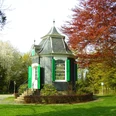 Historisches Gartenhaus Radevormwald Ein kleines, historisches Gartenhäuschen mit Kuppeldach, umgeben von bunten Herbstbäumen im Park.