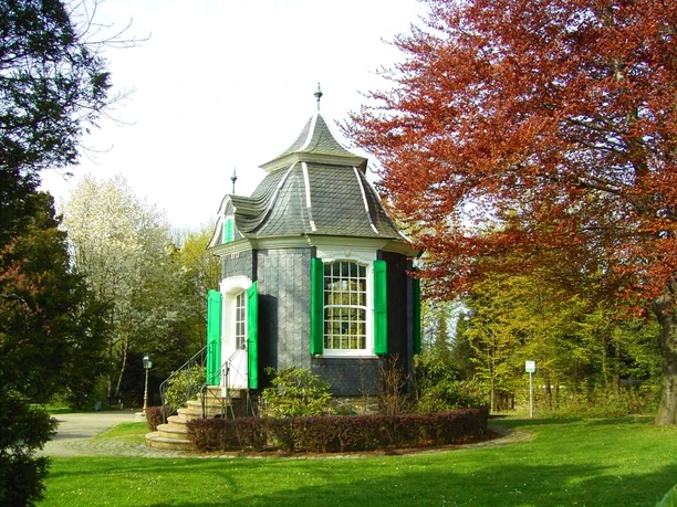 Historisches Gartenhaus Radevormwald Ein kleines, historisches Gartenhäuschen mit Kuppeldach, umgeben von bunten Herbstbäumen im Park.