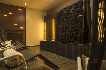 life-ness Ruheraum Ein eleganter Wellnessbereich mit Relaxliegen, sanfter Beleuchtung und einem vertikalen Wasserfall.