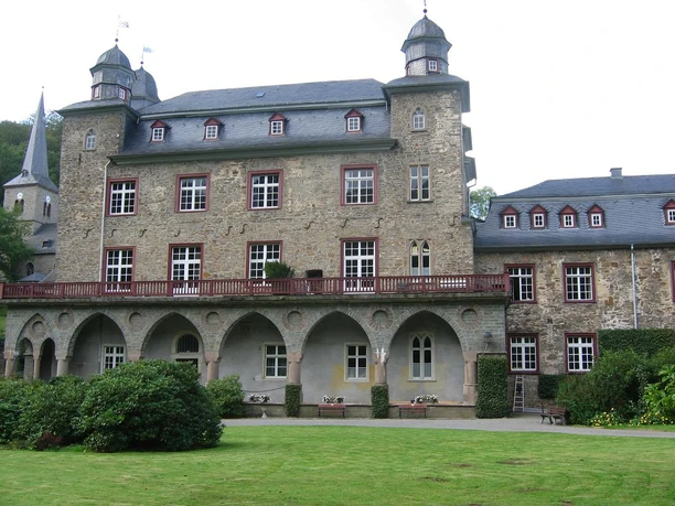 Schloss Gimborn Historisches Schloss mit Türmen und Zinnen, umgeben von gepflegtem Garten und grüner Landschaft.