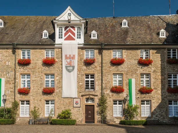 Schloss Hückeswagen <p>Historisches Gebäude in Hückeswagen, Natursteinfassade mit Fensterläden und roten Blumen geschmückt.</p>