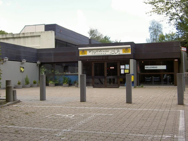 Quellenbad Wermelskirchen Eingangsbereich eines modernen Hallenbads mit Cafeteria, Betongebäude, Pflanzenarrangements.