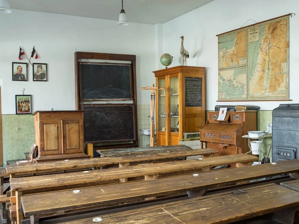 Schulmuseum Bergisch Gladbach Historisches Klassenzimmer mit Holzpult, Landkarten, Schultafel und alten Schulbänken aus Holz.