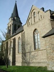 Mediendatei Seitenansicht einer alten, steinernen Kirche mit großen gotischen Fenstern und einem hohen Turm.