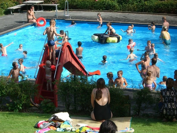 Waldfreibad Kinder und Erwachsene genießen das Schwimmen und Spielen in einem belebten Freibad mit Rutsche.