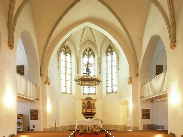 Kirchenschiff Gotische Kirche mit hohen Gewölbedecken, hölzernen Kirchenbänken und einem beeindruckenden Altar.