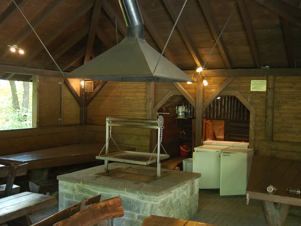 Grillhütte Windfus Rustikale Grillhütte mit Holzbänken, offenem Kamin und hölzernem Dachgebälk in einem gemütlichen Ambiente.