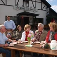 Bewirtung auf dem Pferdehof Hacke Eine Gruppe älterer Menschen sitzt an einem Holztisch vor einem Gasthof und genießt Kaffee.