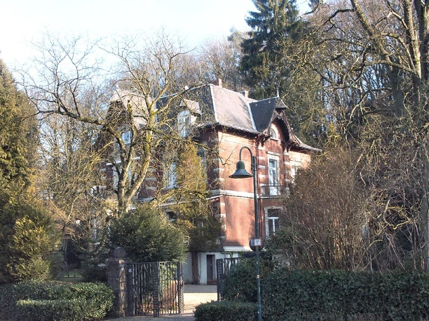 Villa Kurt Reusch Historisches Backsteinhaus mit Dachgauben, umgeben von Bäumen und Laterne im Vordergrund.