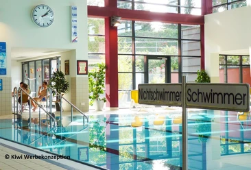 Schwimmbecken Innenansicht eines Schwimmbades mit Uhr an der Wand, Schwimmbecken und Sitzbereich.