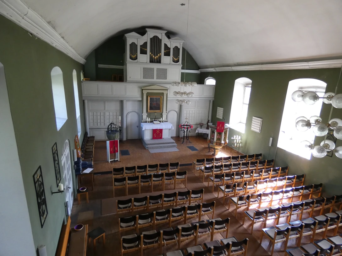 Kirchengemeinde Zum Guten Hirten Ein lichtdurchfluteter Kirchenraum mit geschmücktem Altar, Bestuhlung und einem Orgelprospekt.