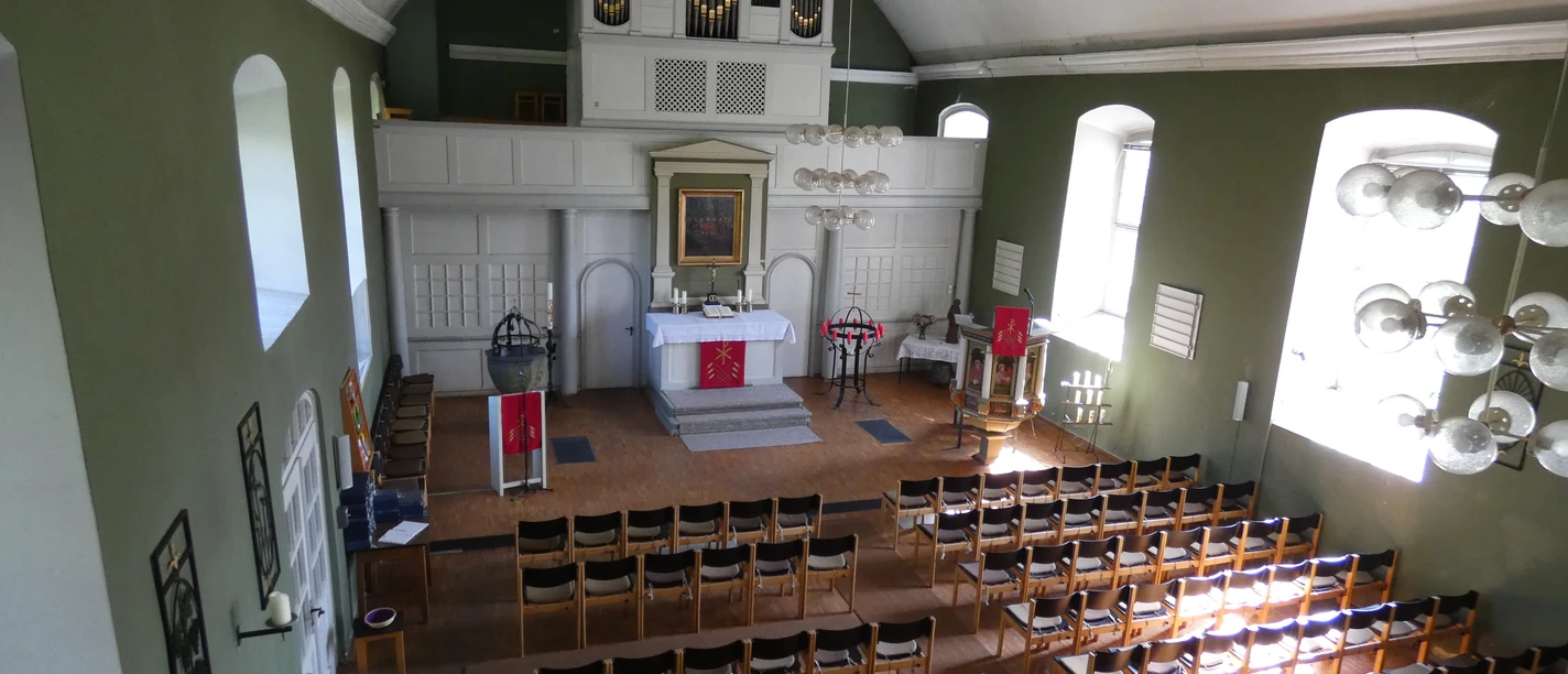 Kirchengemeinde Zum Guten Hirten Ein lichtdurchfluteter Kirchenraum mit geschmücktem Altar, Bestuhlung und einem Orgelprospekt.