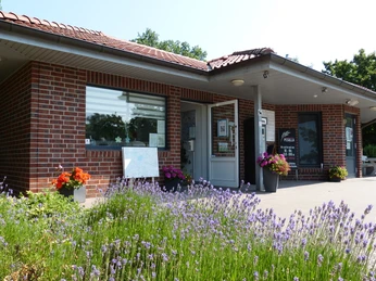 Ziegelgebäude mit Flachdach, flankiert von blühendem Lavendel, markiert den Eingang zum Stellplatz.