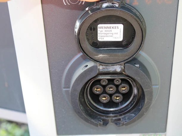 Detailansicht eines geöffneten Mennekes-Ladeanschlusses für Elektrofahrzeuge.
