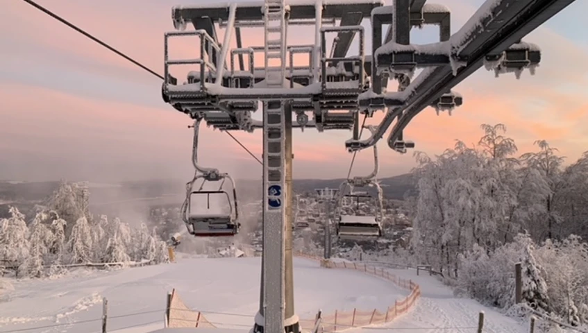 Wurzelrudi_Winter©Wurzelrudi02.jpg Schneebedeckter Sessellift in winterlicher Landschaft, Abendhimmel im Hintergrund.