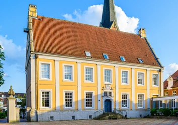 Dankelman´sches Palais Amtsgericht Barockbau mit gelber Fassade, weißen Fensterrahmen und rotem Ziegeldach unter blauem Himmel.