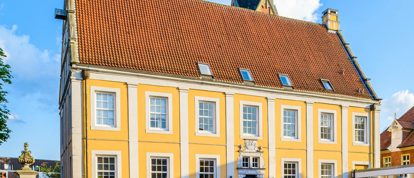 Dankelman´sches Palais Amtsgericht Barockbau mit gelber Fassade, weißen Fensterrahmen und rotem Ziegeldach unter blauem Himmel.