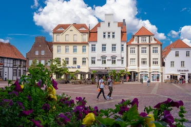 Marktplatz mit alten Bürgerhäusern Historischer Marktplatz in Lingen mit bunten Bürgerhäusern, Straßencafé und blühenden Pflanzen.