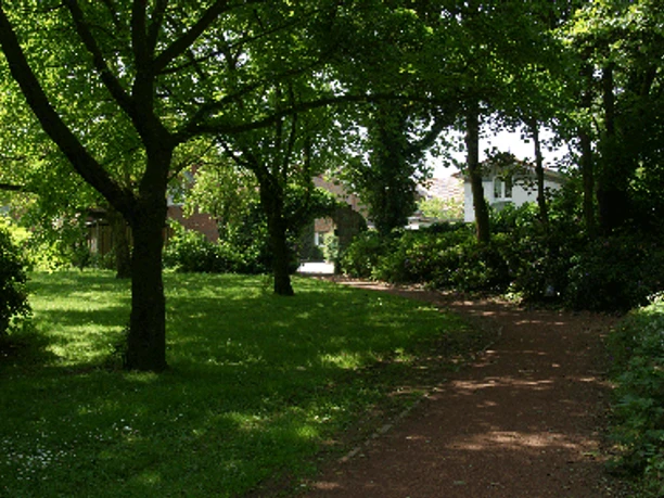 Garten der Justiz Amtsgerichtpark Grüner Parkweg unter schattigen Bäumen mit Blick auf historische Gebäude im Garten der Justiz.