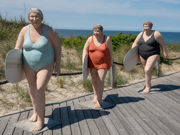 Drei Surferinnen auf der Promenade