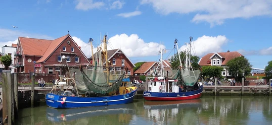 neuharlingersiel Hafen von Neuharlingersiel mit bunten Fischerbooten und traditioneller Backsteinarchitektur im Hintergrund.