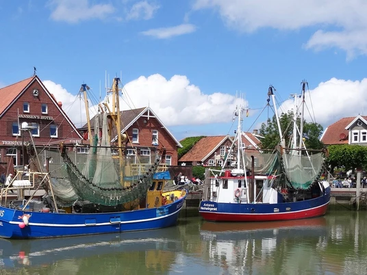 neuharlingersiel Hafen von Neuharlingersiel mit bunten Fischerbooten und traditioneller Backsteinarchitektur im Hintergrund.