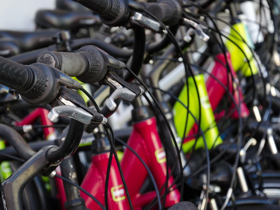 Fahrradverleih Mehrere Fahrräder stehen nebeneinander gereiht, in den Farben rot, gelb und weiß