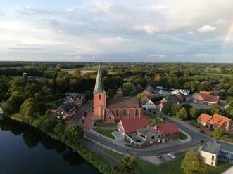 St.-Georgs-Kirche in Steinbild Backsteinkirche mit hohem Turm im Zentrum von Steinbild, umgeben von Wasser, Wiesen und Wohnhäusern.