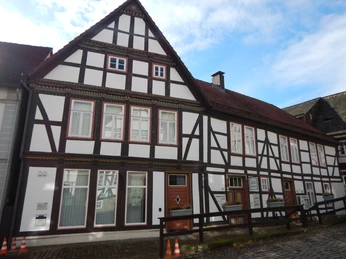 Fachwerkhaus mit weißen Wänden, Tourist-Info und Galerie in Schwalenberg unter blauem Himmel.