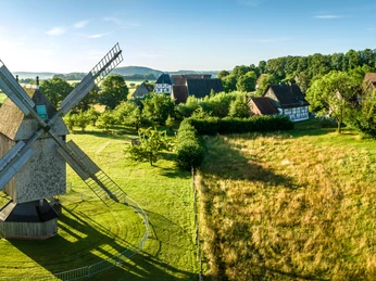 Historische Windmühle im Freilichtmuseum Detmold, umgeben von grünen Wiesen und Fachwerkhäusern.