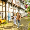 Ein Paar spaziert bei Sonnenschein durch eine idyllische Fachwerkgasse in Detmold.