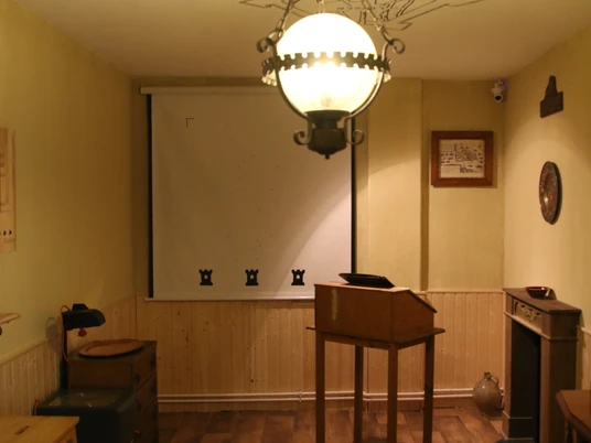 Room Fox - #1 Escape Room Emsland Ein Rätselraum mit Holzmöbeln, warmem Licht und geheimnisvollen Details an Wand und Decke.