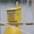 Gelbe Postboje auf dem Stillen Wasser des Steinhuder Meers mit Postkasten für schwimmende Post.