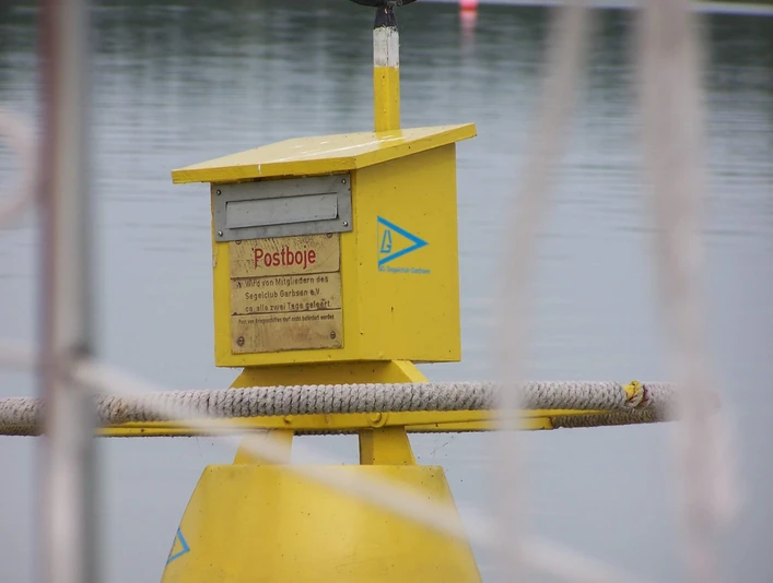 Gelbe Postboje auf dem Stillen Wasser des Steinhuder Meers mit Postkasten für schwimmende Post.