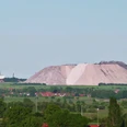 Kalimanscharo Große Halde aus Salzabraum in grüner Landschaft mit einem Heißluftballon am klaren Himmel im Hintergrund.