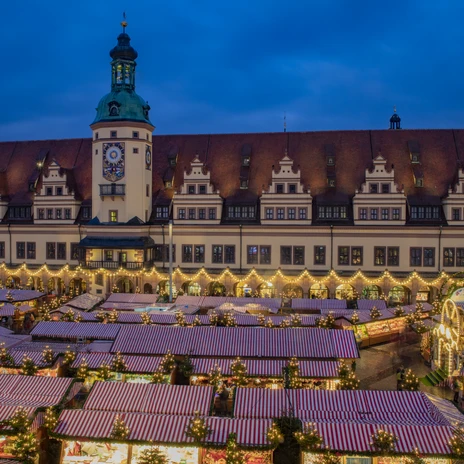Noční vánoční trh v Lipsku, osvětlené stánky před historickou Starou radnicí.
